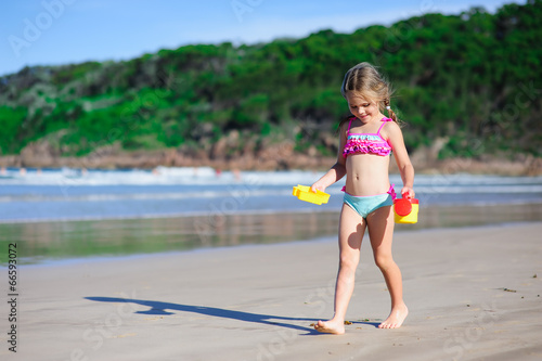 little girl on a sandy beach play with toys
