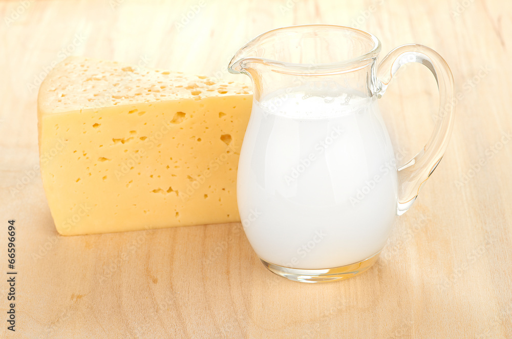 Big piece of cheese, glass jug with milk Big piece of cheese, glass jug with milk