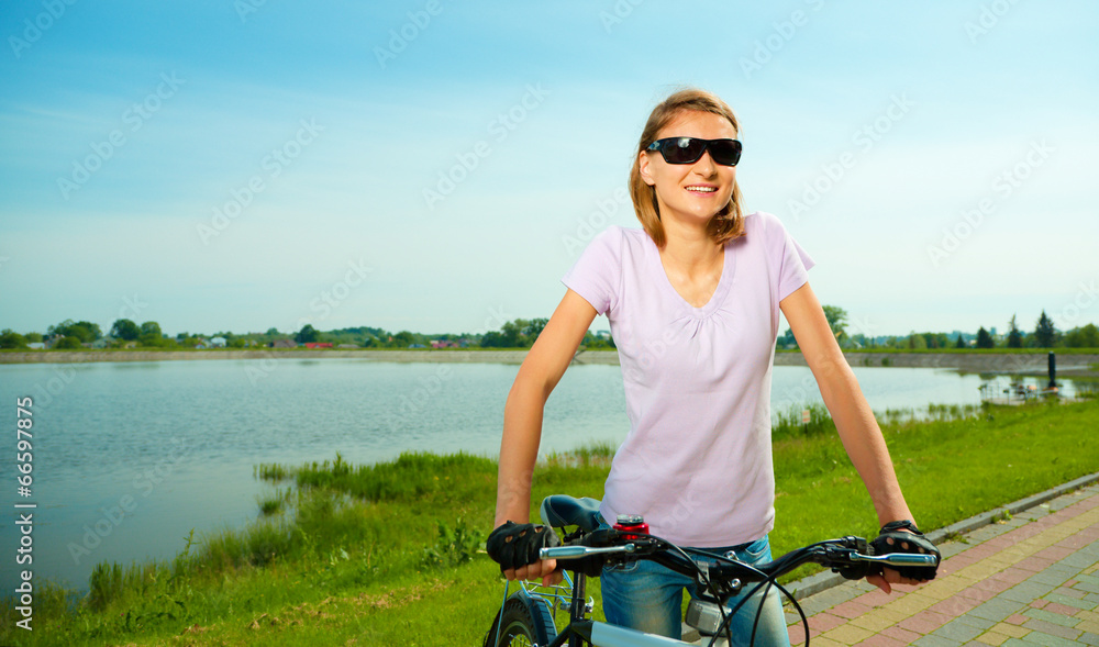 Young woman is standing behind bicycle Young woman is standing behind bicycle