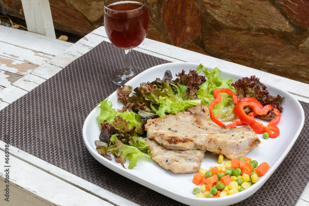 Grilled pork on white plate with glass of wine Grilled pork on white plate with glass of wine