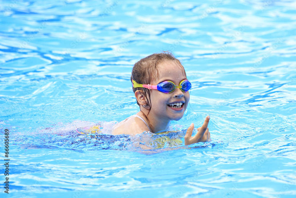 Joyful child in swimming glasses in the outdoor pool.