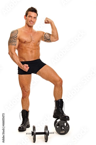 Handsome muscular man standing poses with dumbbell