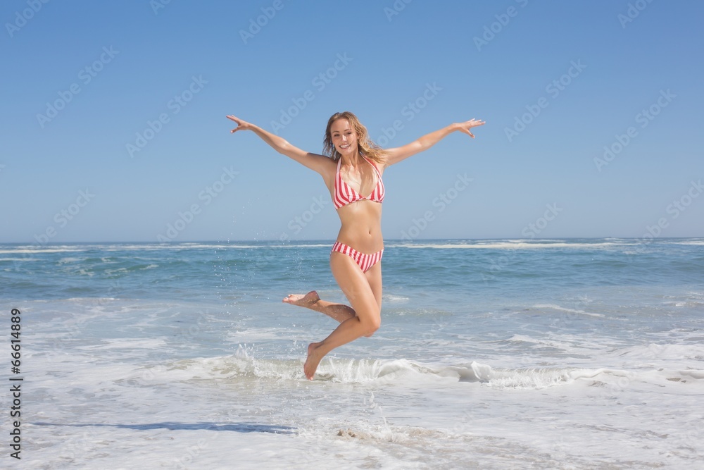 Happy fit woman in bikini jumping on the beach Happy fit woman in bikini jumping on the beach