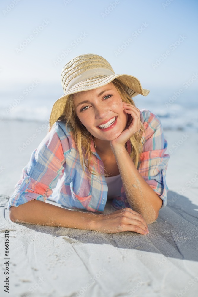 Pretty blonde smiling at camera at the beach lying on the sand