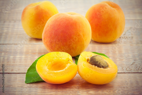 Ripe peaches with leaves on wooden table