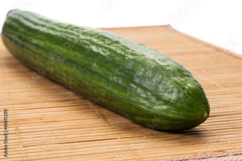 Big green cucumber on a wooden plate.