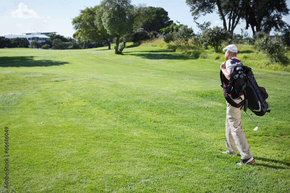 Golf player carrying his bag and walking