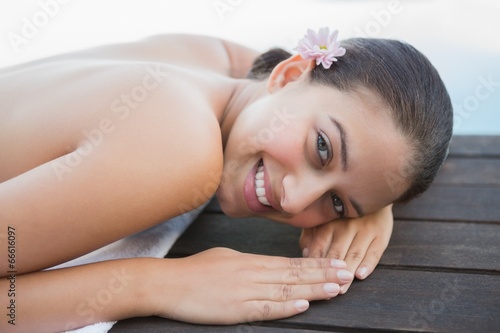Peaceful brunette lying on towel smiling at camera