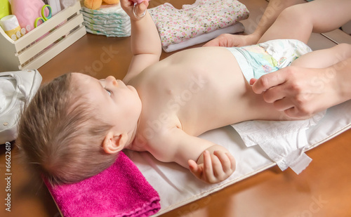 Fotografie Mother changing diaper of adorable baby