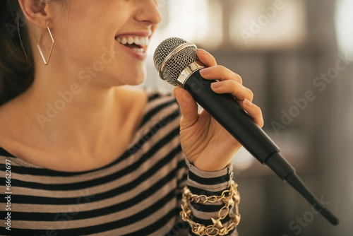 Fototapeta Closeup on happy young woman singing with microphone