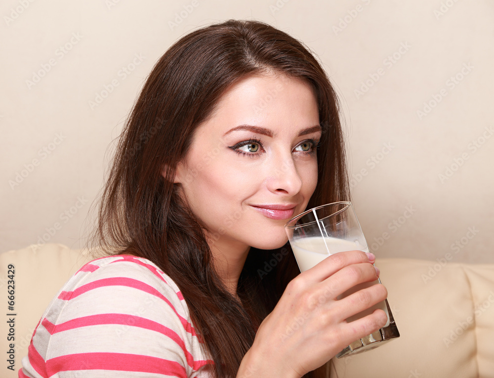 Happy woman drinking milk from glass sitting on sofa Happy woman drinking milk from glass sitting on sofa