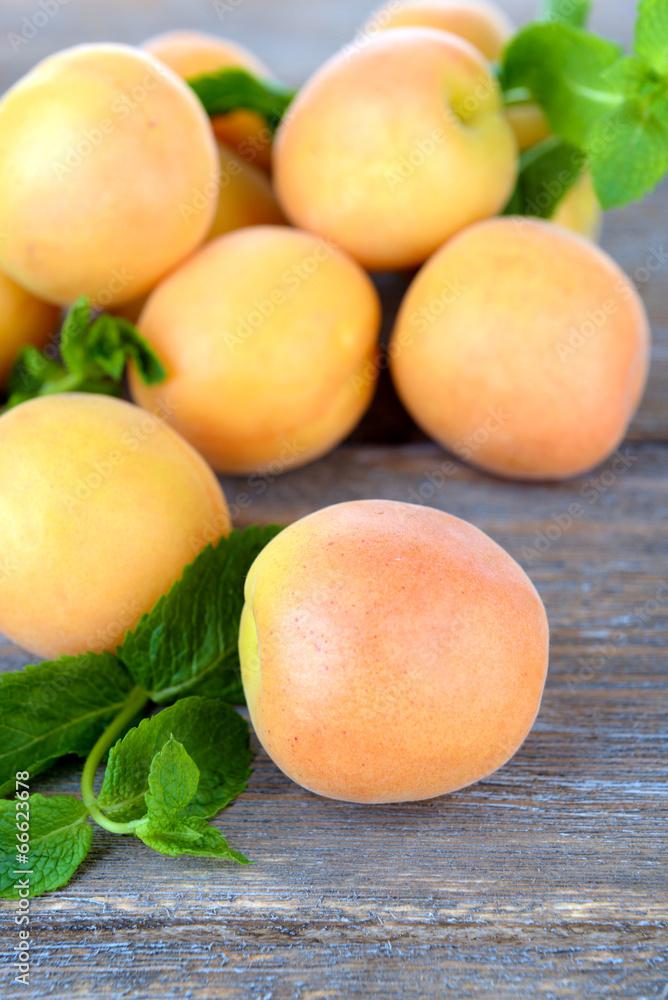Ripe apricots with green mint leaves on wooden background Ripe apricots with green mint leaves on wooden background