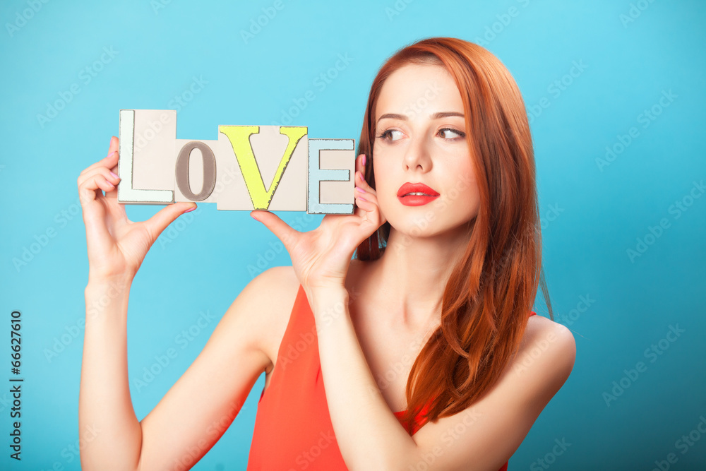 Surprised redhead women with word Love on blue background. Surprised redhead women with word Love on blue background.