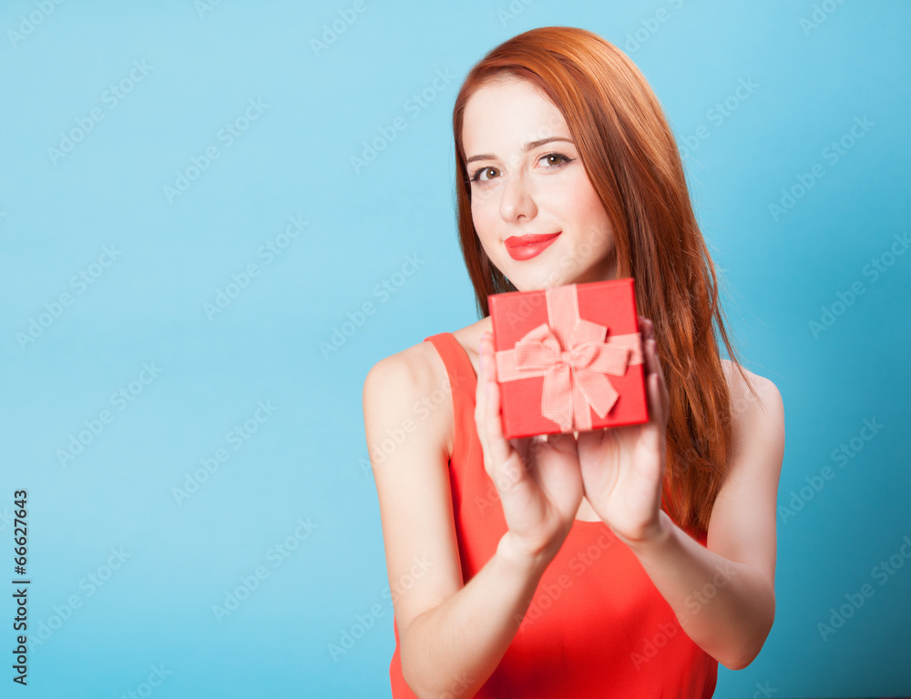 Smiling redhead women with gift on blue background. Smiling redhead women with gift on blue background.