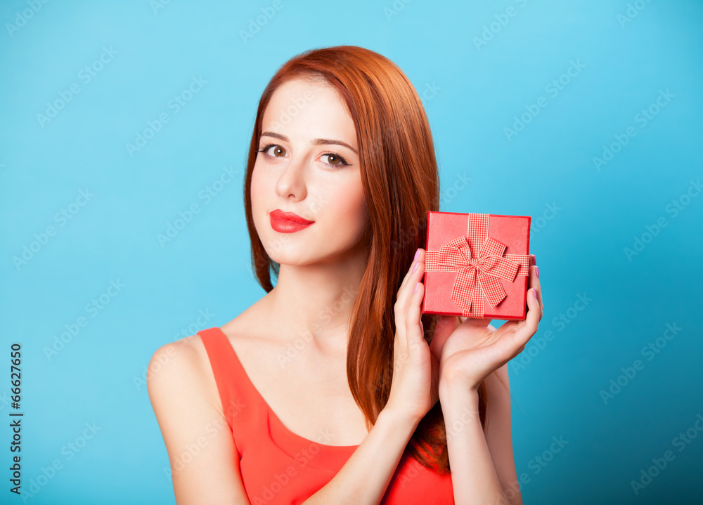 Smiling redhead women with gift on blue background. Smiling redhead women with gift on blue background.