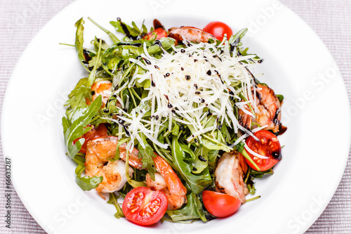 Salad with arugula and shrimps in a white plate