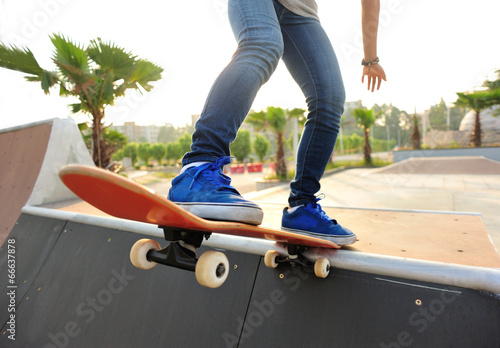 woman skateboarder legs skateboarding at skatepark photo