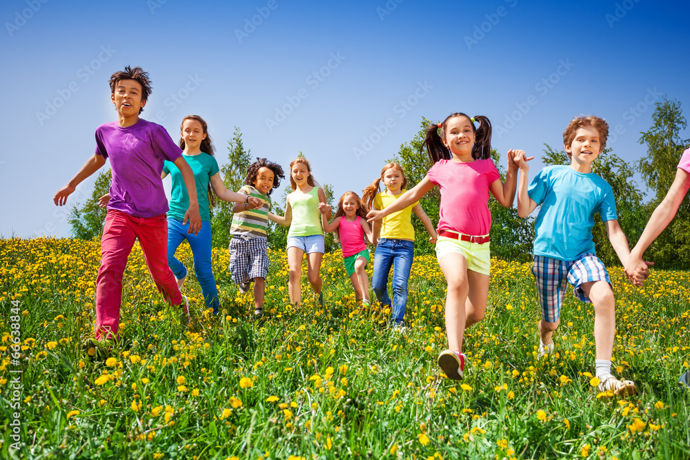 Happy kids run and hold hands in green meadow Happy kids run and hold hands in green meadow