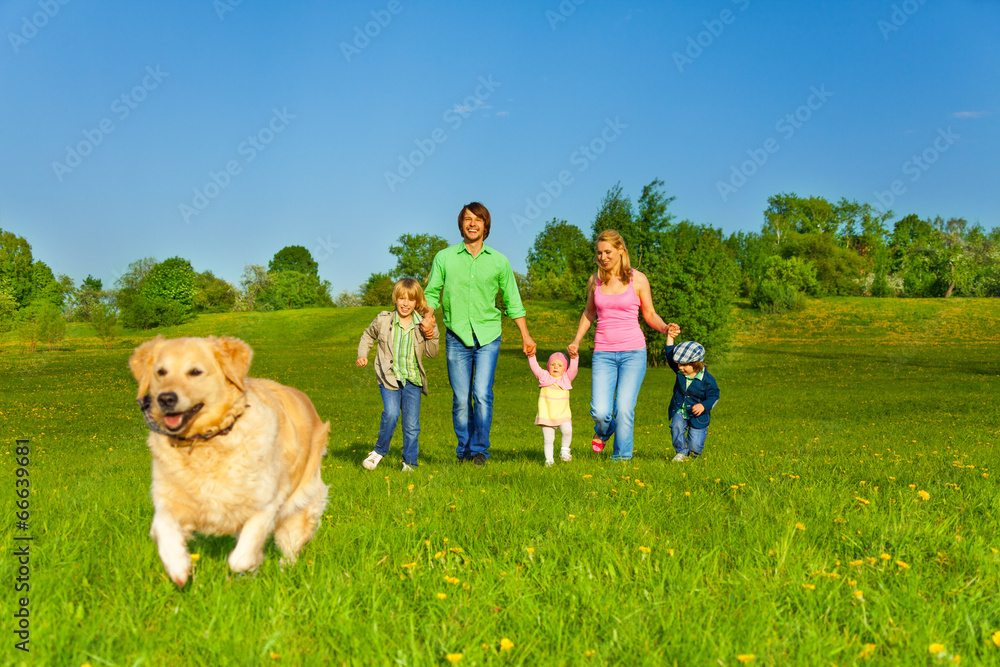 family walks with running dog in park family walks with running dog in park
