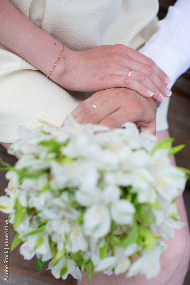 Hands of bride and groom holding wedding bouquet Hands of bride and groom holding wedding bouquet