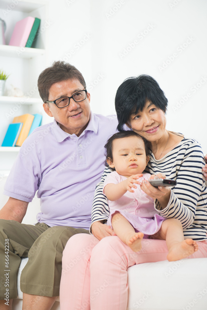 asian grand parents watching television with grand daughter life