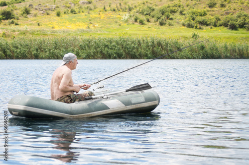 Senior man fishing from a dinghy in a lake