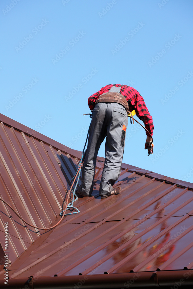 Roofer builder worker with pulverizer spraying paint on roof Roofer builder worker with pulverizer spraying paint on roof