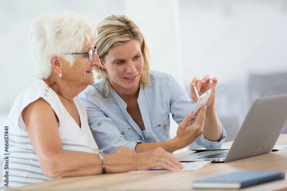 Fototapeta premium Homehelp with elderly woman using smartphone