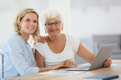 Homecarer with elderly woman using laptop computer