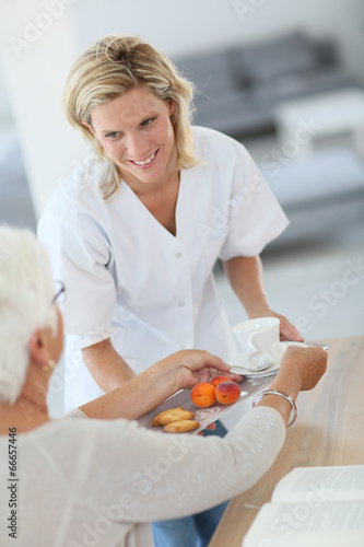 Homecarer giving tea to elderly woman photo