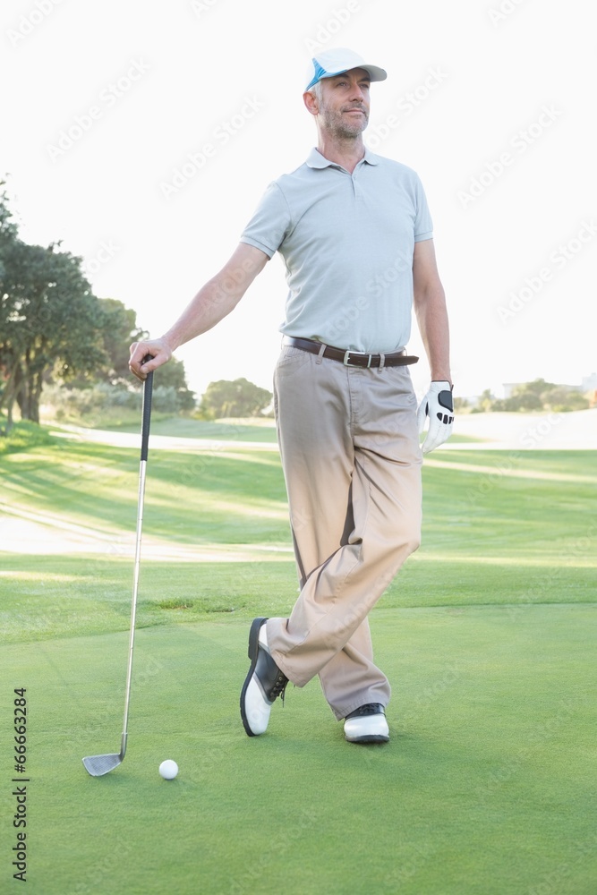 Handsome golfer standing with club