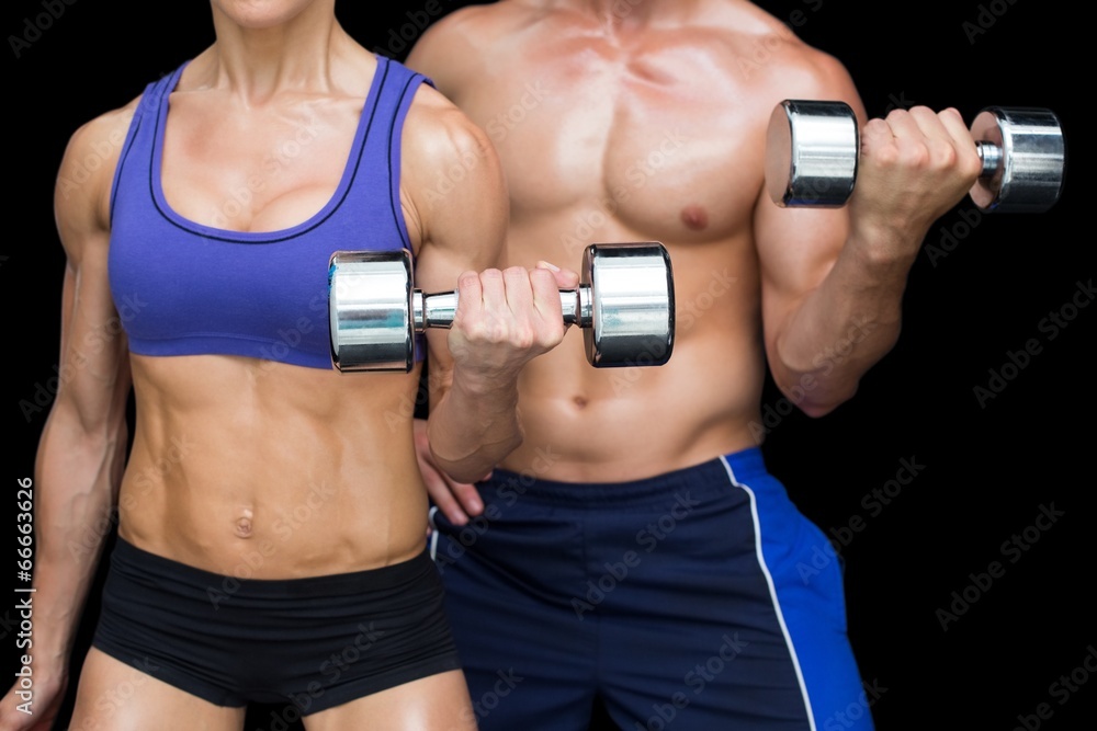 Bodybuilding couple posing with large dumbells Bodybuilding couple posing with large dumbells