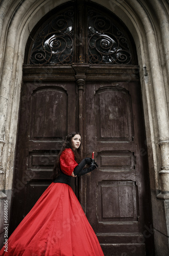 Mysterious woman in Victorian dress with old doors