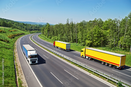 The highway between forests with three oncoming trucks