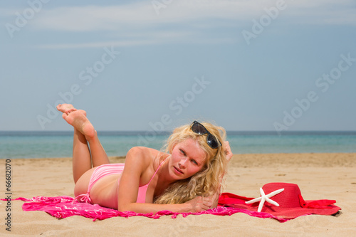 Young woman in red bikini holding sarong on the beach