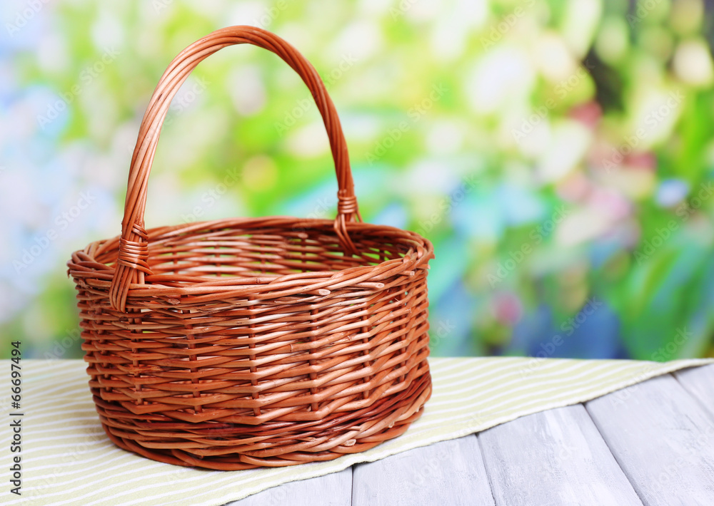 Empty wicker basket on wooden table, on bright background Empty wicker basket on wooden table, on bright background