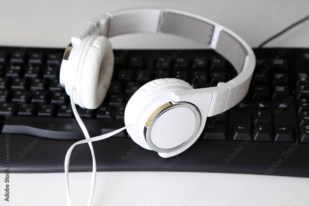 Headphone and keyboard close-up on white desk background Headphone and keyboard close-up on white desk background