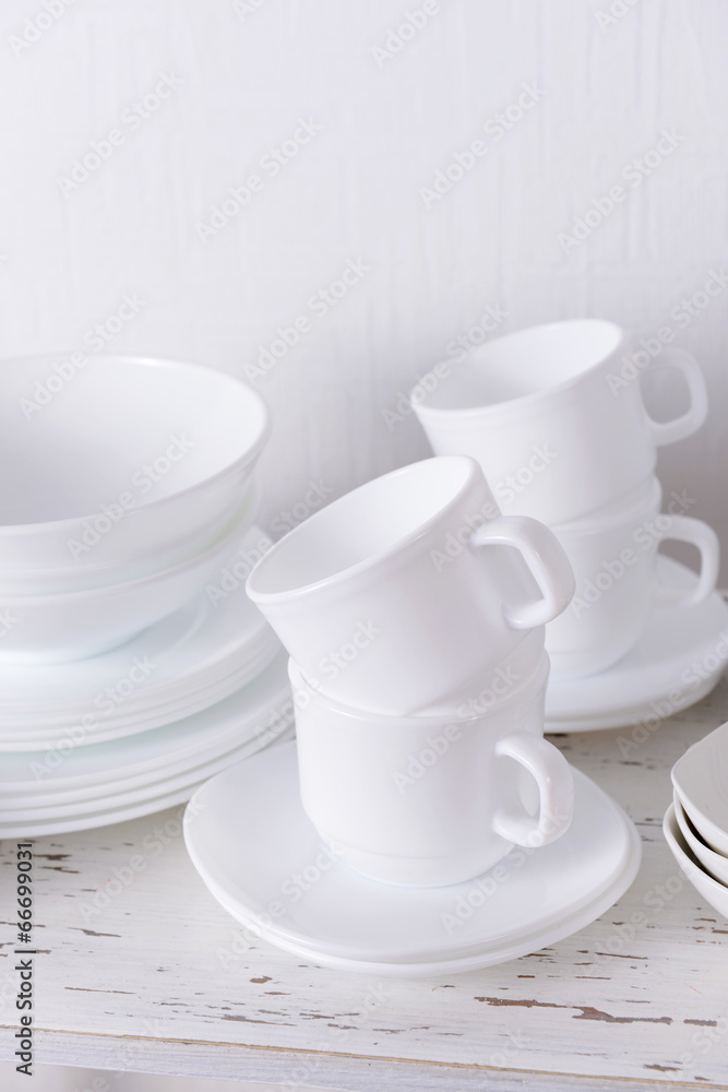 Set of white dishes on table on light background Set of white dishes on table on light background