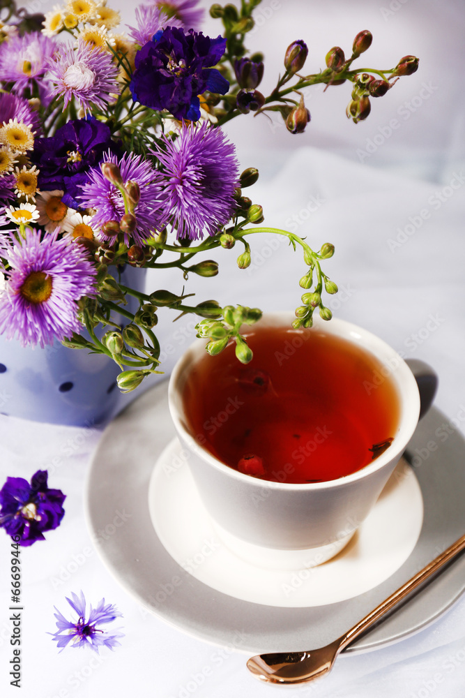 Cup of fresh herbal tea and beautiful bouquet of wildflowers Cup of fresh herbal tea and beautiful bouquet of wildflowers