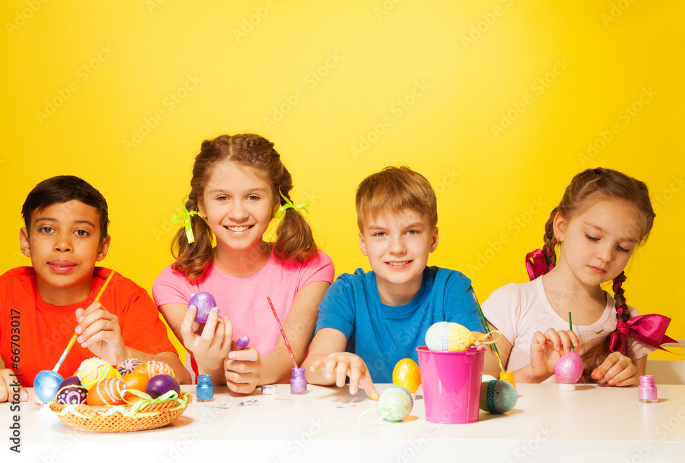 Four children colour Easter eggs at the table Four children colour Easter eggs at the table