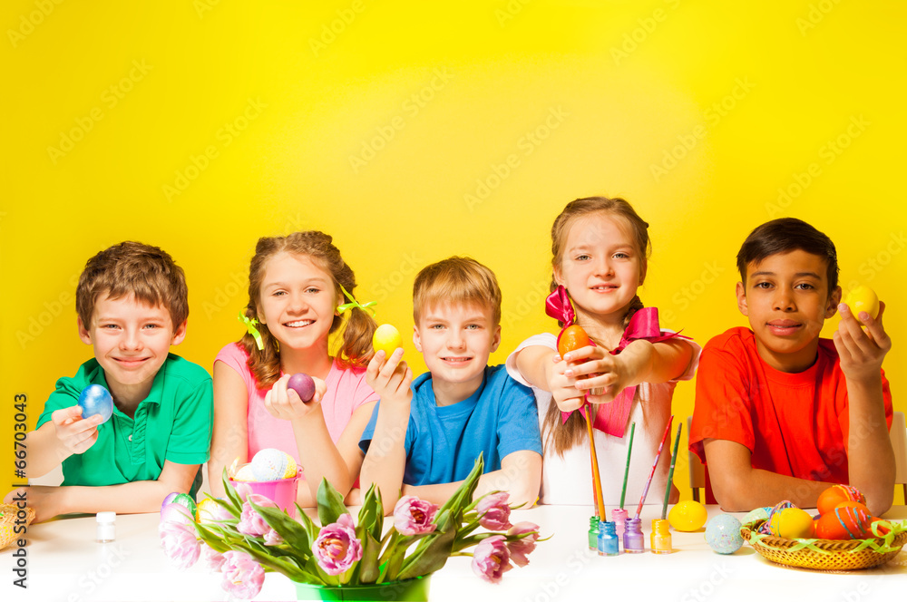 Five kids holding coloured Easter eggs at table Five kids holding coloured Easter eggs at table