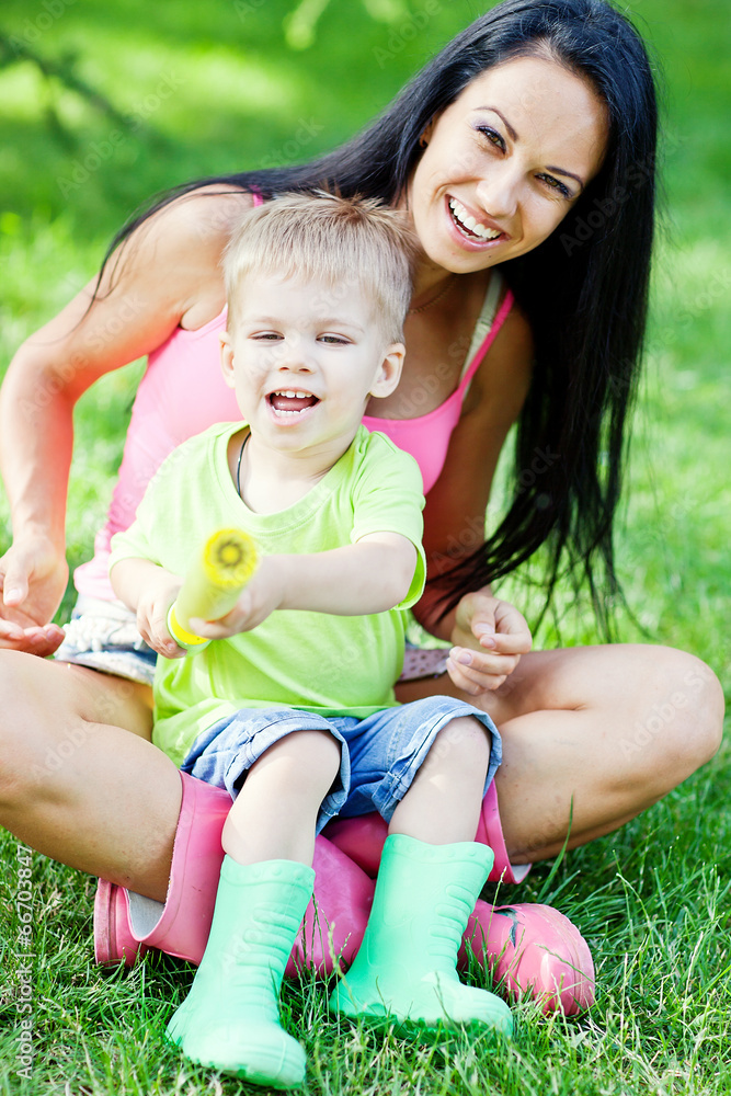 Young mother and her little son outdoors in colorful rubber boot