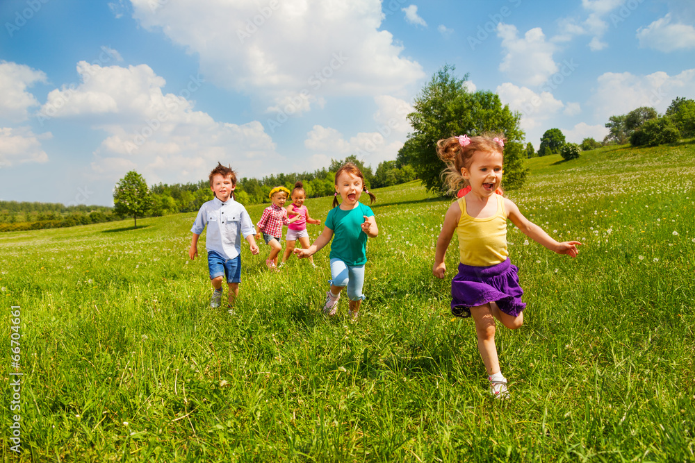 Running children in green field during summer