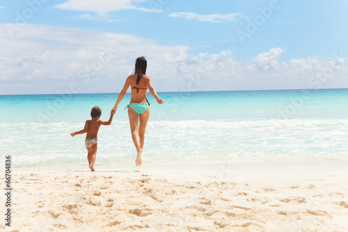 Child and woman running to the sea holding hands
