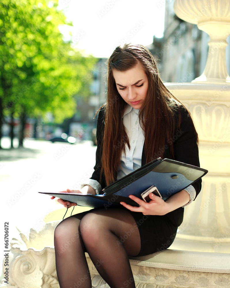 Obraz premium Young business woman working with a folder of documents sitting