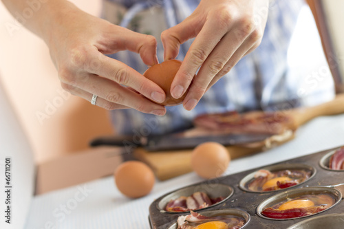 Woman cracking an egg into a muffin pan