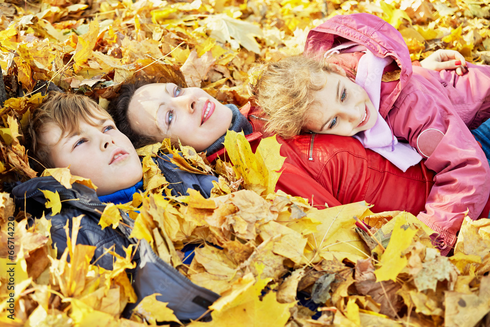 Mother and children lie in autumn park in drift Mother and children lie in autumn park in drift