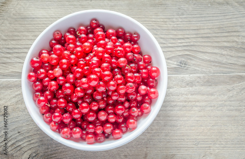 Bowl with fresh redcurrant on the wooden table