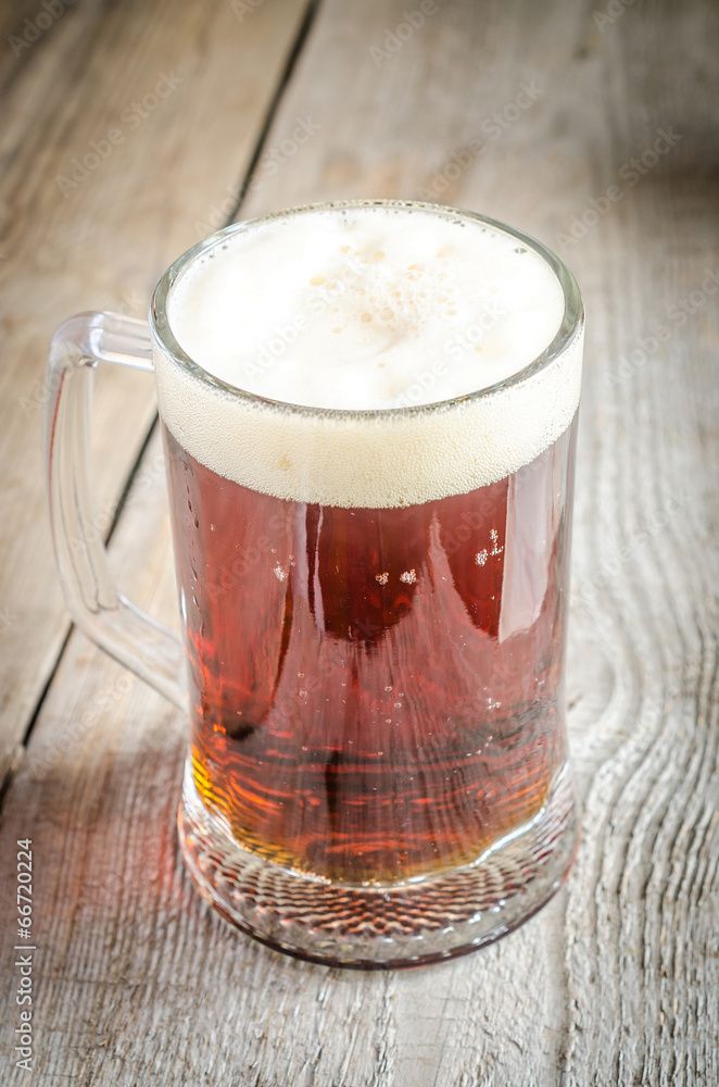 Mug with dark beer on the wooden table Mug with dark beer on the wooden table