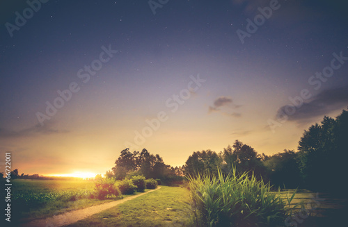 Sonnenuntergang und Sterne am Feldweg mit See